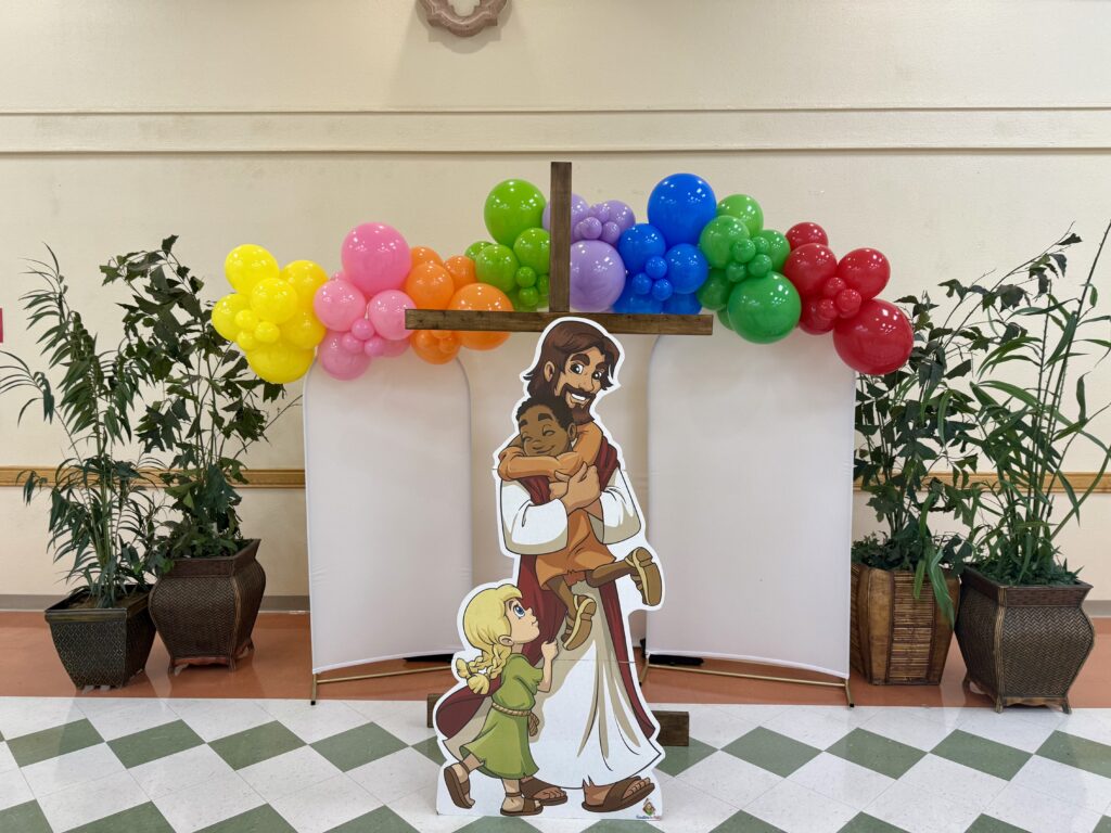 Christian event balloon decoration with cross backdrop and colorful balloon garland