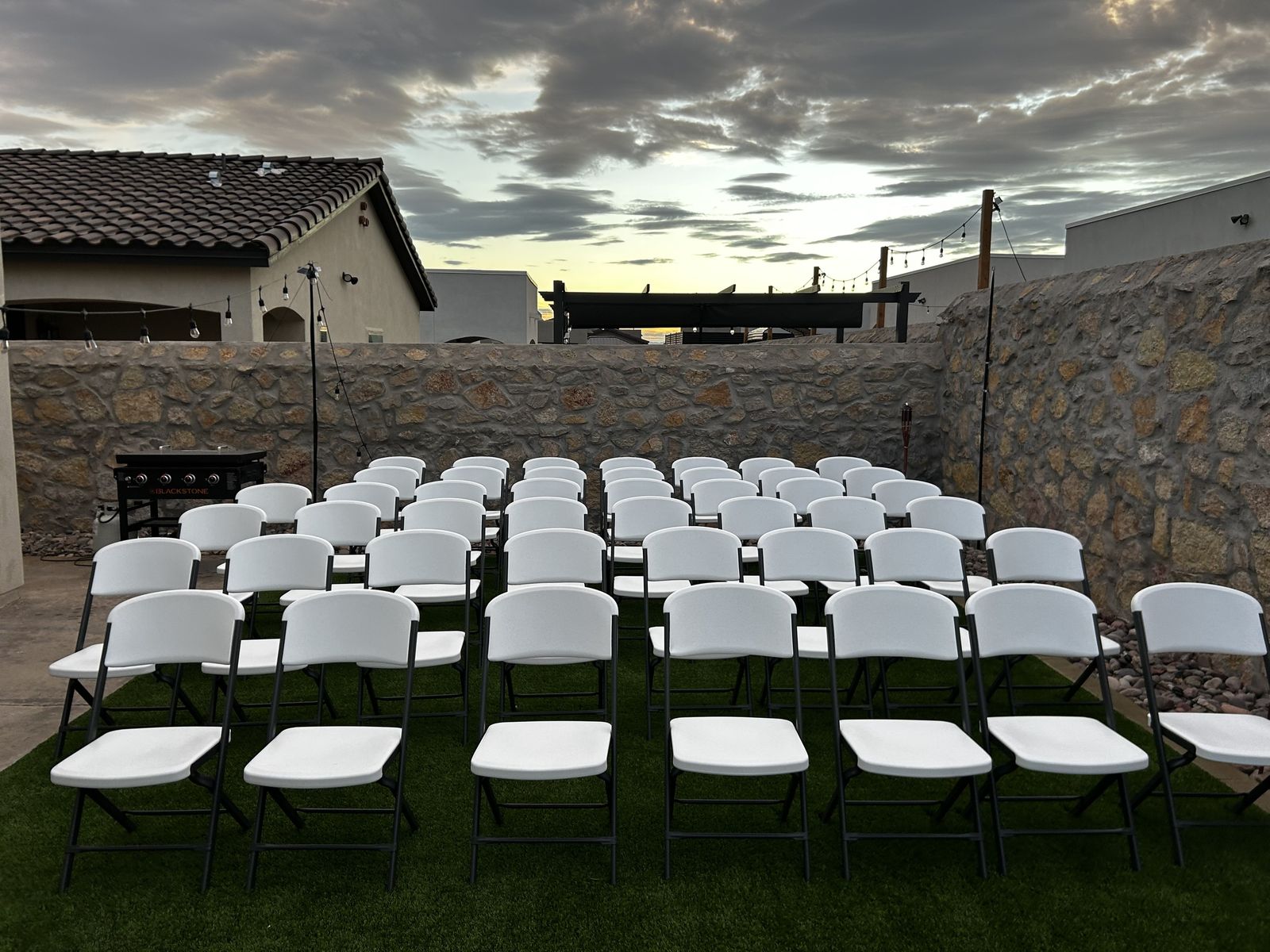 Rows of white Lifetime chairs set for an outdoor ceremony at sunset in El Paso