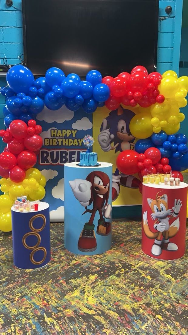 Decorated cylinder stands holding a cake and treats at a birthday party