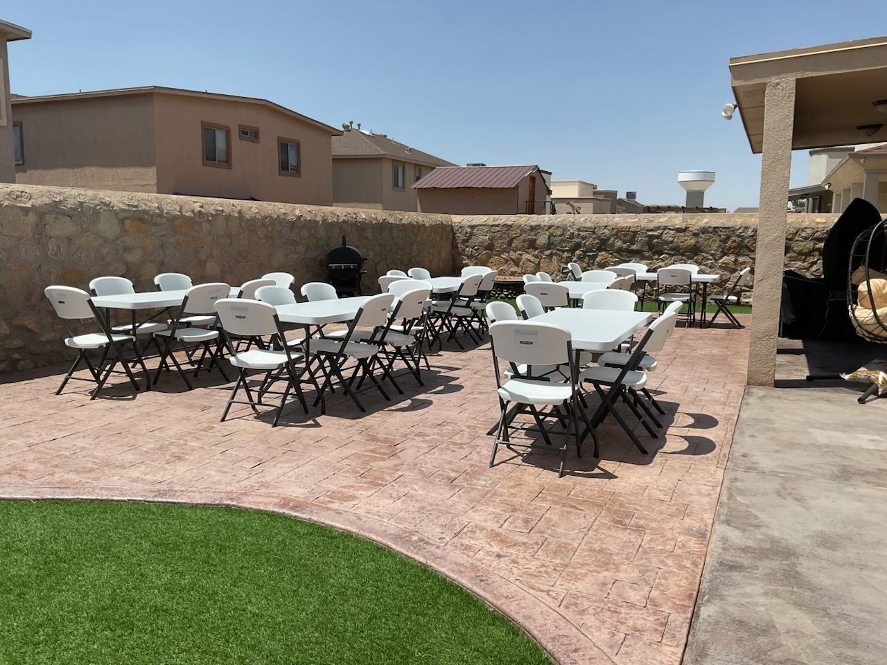 6 ft tables and white Lifetime chairs set up on a backyard patio in El Paso