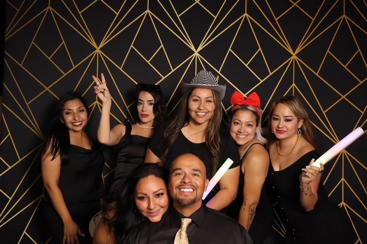 Group in front of the black and gold photo booth backdrop