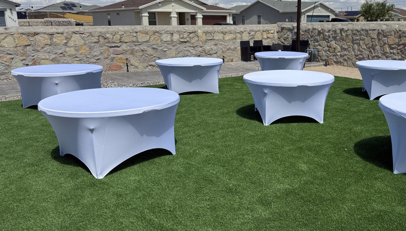 60 inch round tables with white spandex covers set up in an El Paso backyard